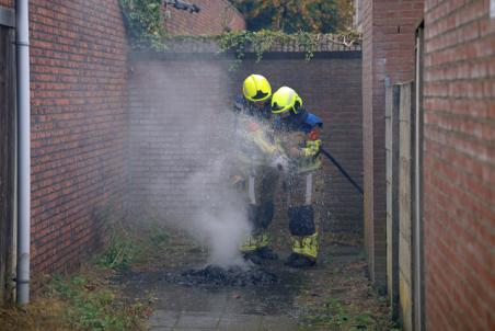 Berg papier in brand in brandgang aan de Drogerij Waalwijk