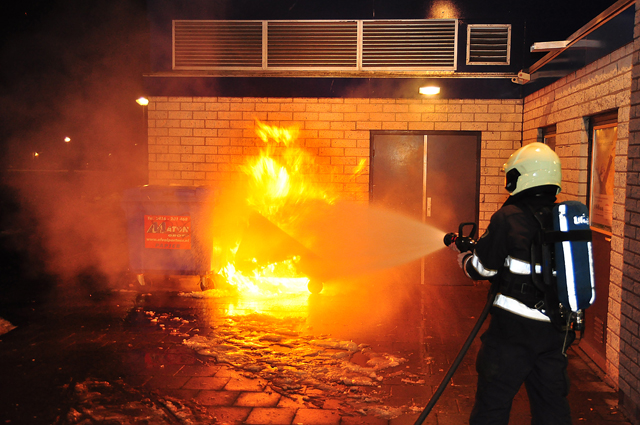Container staat in brand tegen winkelpand aan de Prof. De Savornin Lohmanpark Waalwijk