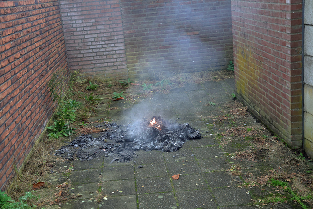 Berg papier in brand in brandgang aan de Drogerij Waalwijk