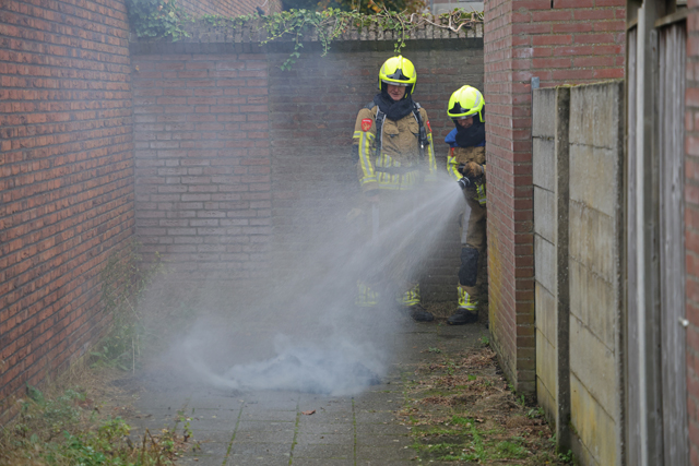 Berg papier in brand in brandgang aan de Drogerij Waalwijk