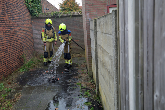 Berg papier in brand in brandgang aan de Drogerij Waalwijk