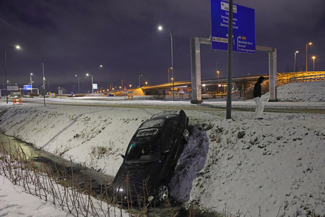Automobilist belandt in sloot door sneeuw en wacht rustig af met hamburger en stoeltje in Waalwijk
